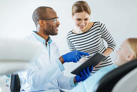 Dentist discussing child's dental health with the child's mother and looking at insurance coverage