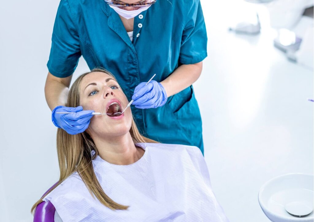 Dentist examining a patient's mouth for signs of an infected tooth, including swelling, tenderness, and possible dental infection.