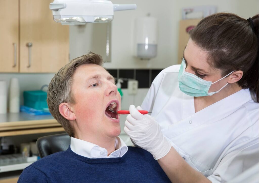 Dentist examining a patient's gums during an oral exam to check for gingivitis symptoms such as redness, swelling, and bleeding.