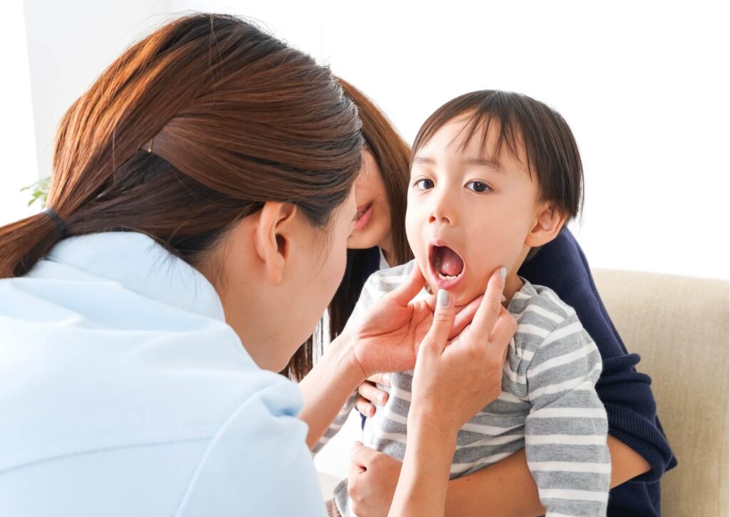 Pediatric dentist examining a young child's mouth to determine whether a kids dental spacer is needed after early tooth loss.
