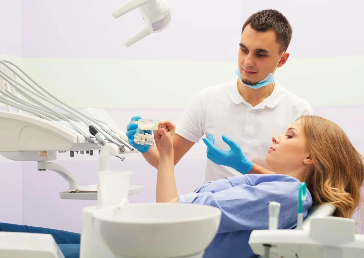 Dentist explaining the tooth implant process and treatment timeline to a patient during a consultation.