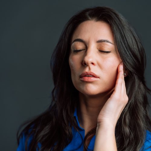 A woman rubs her jaw in discomfort - naccid buford dentist, GA