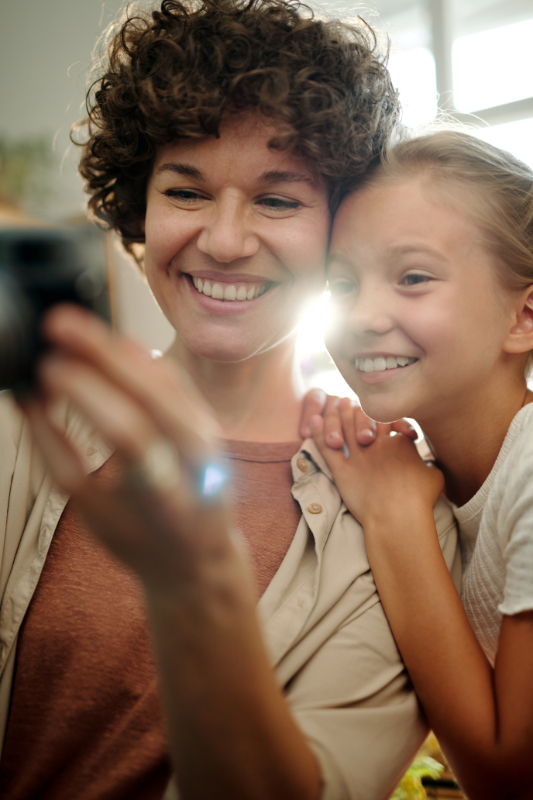 mother and daughter smiling for a selfie with youthful smiles 